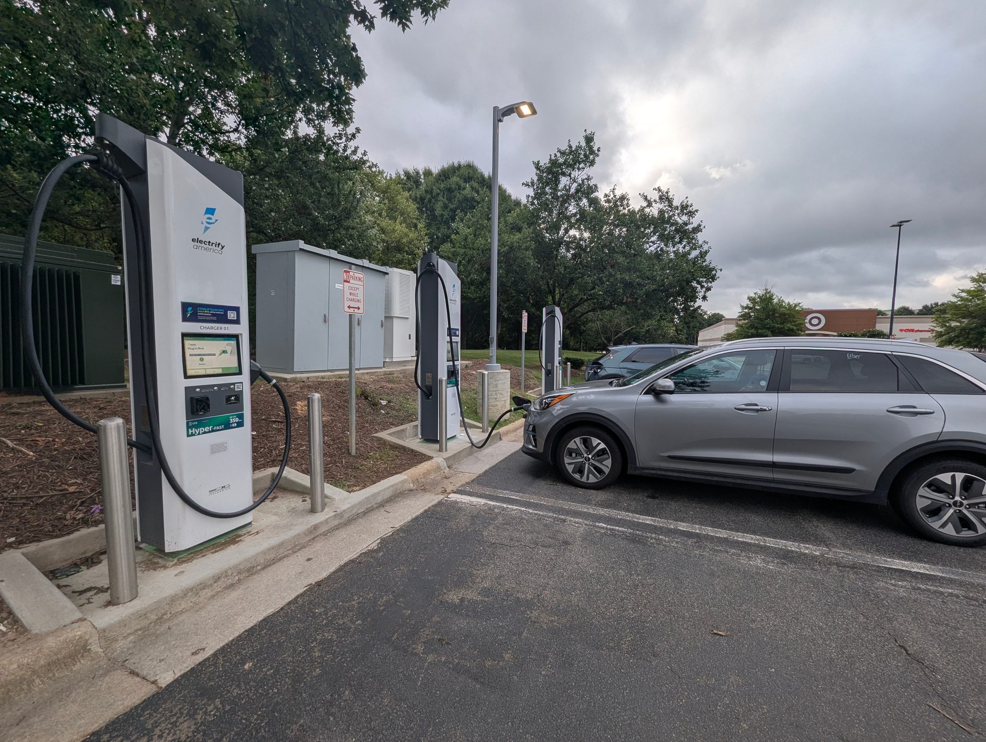 Electric SUV parked beside DC fast charging stations at a roadside charging stop