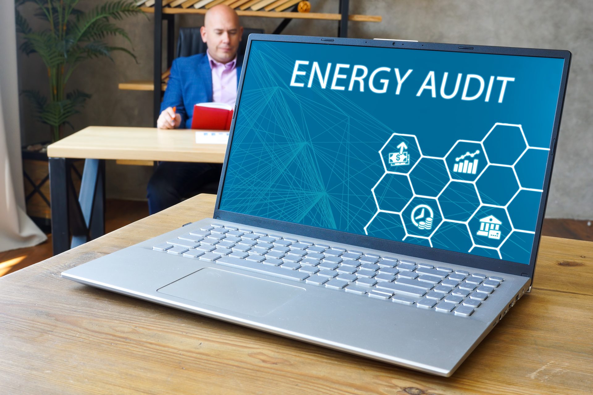 Business owner at a desk behind a laptop showing an energy audit dashboard