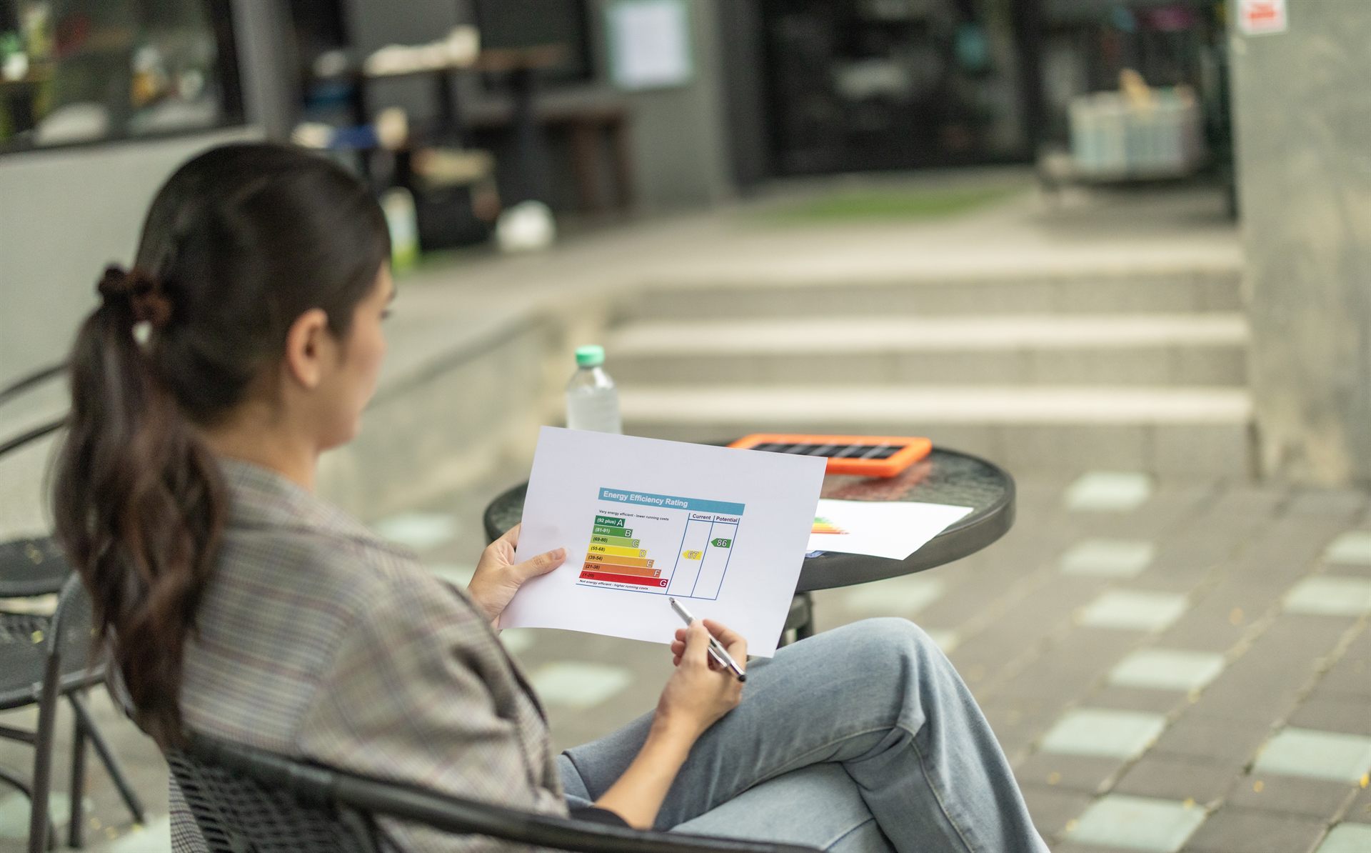 Small cafe owner reviewing an energy efficiency rating chart at an outdoor table